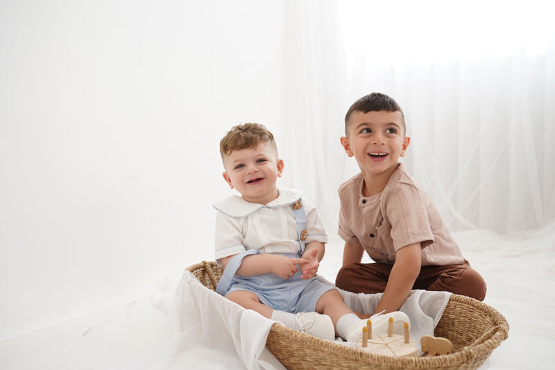 Two young boys sitting in a woven basket on a white background