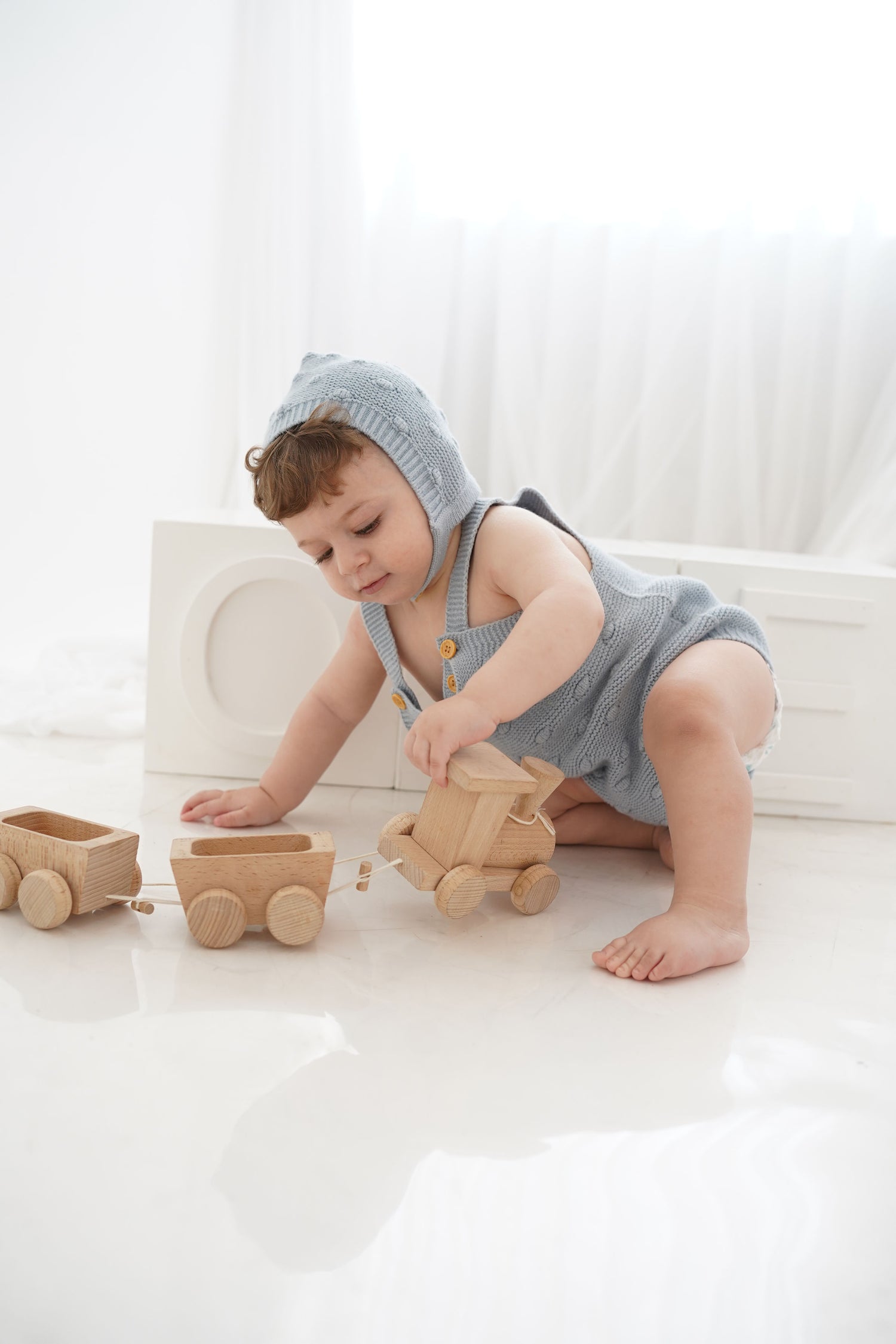 Child playing with wooden toys on a white floor